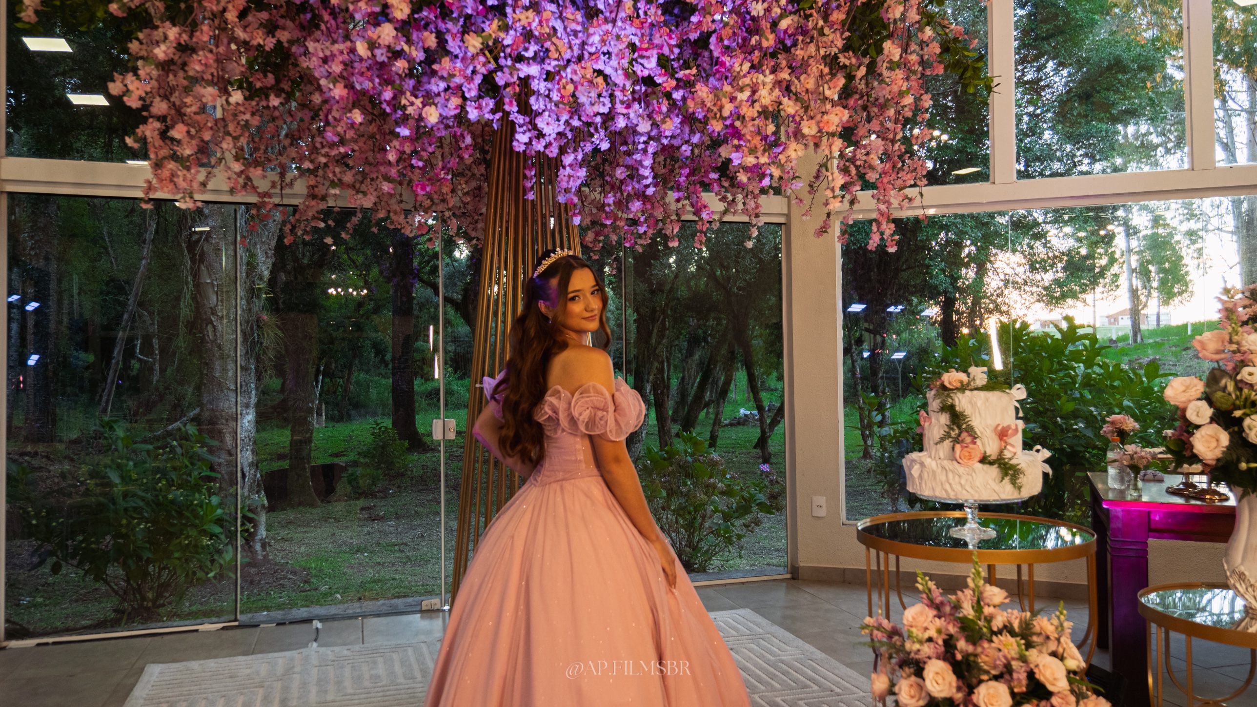 Debutante olhando por cima do ombro no salão decorado, ao lado do bolo