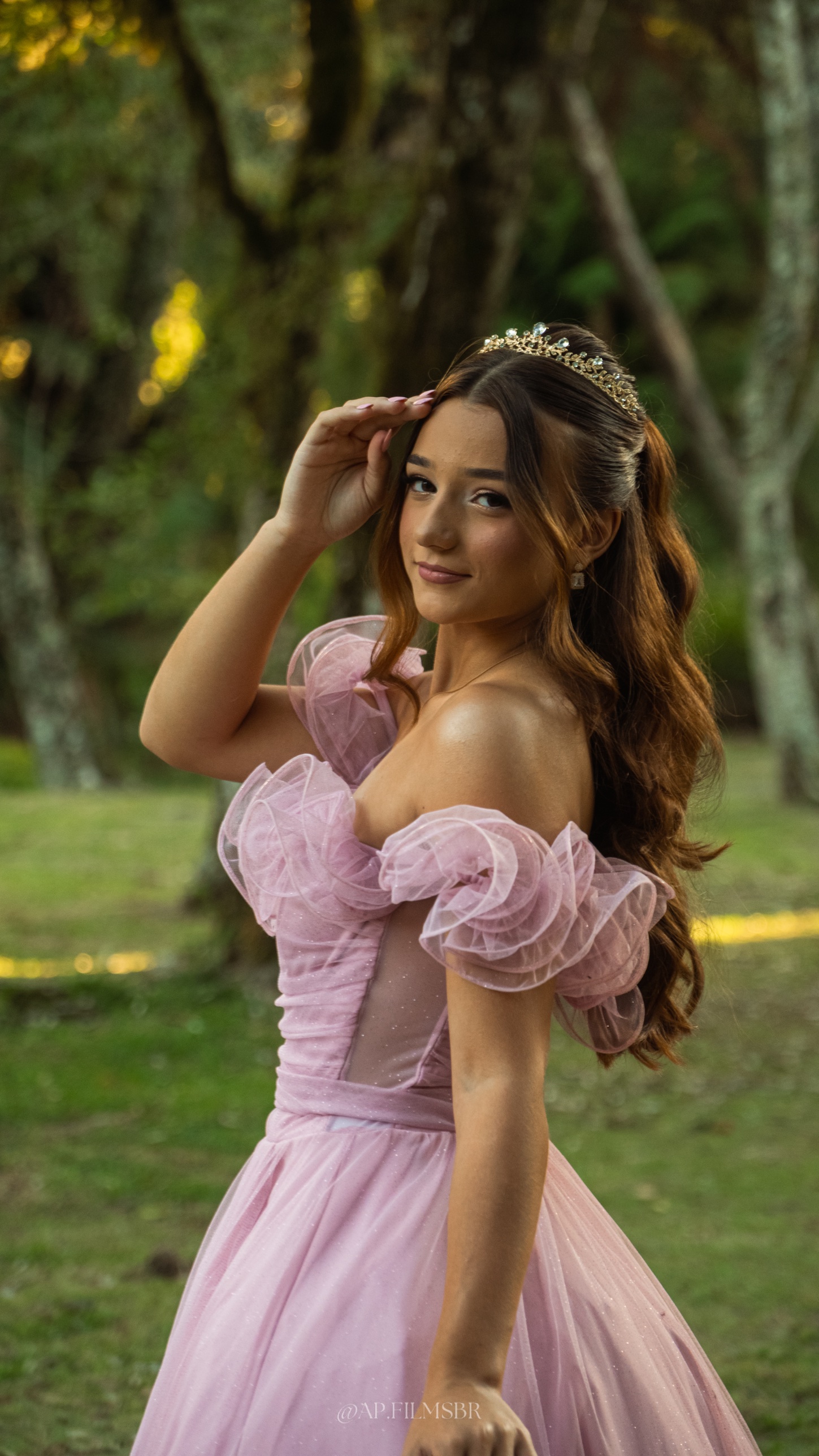 Debutante com a mão no cabelo, em meio às árvores