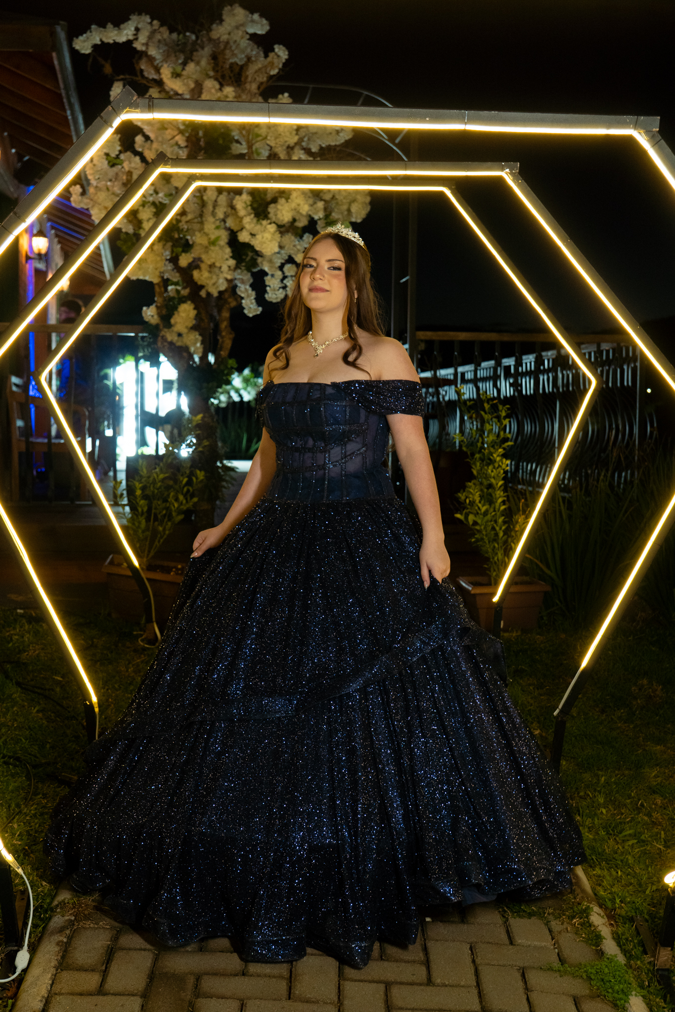 Debutante de vestido azul brilhante entre arcos de luz