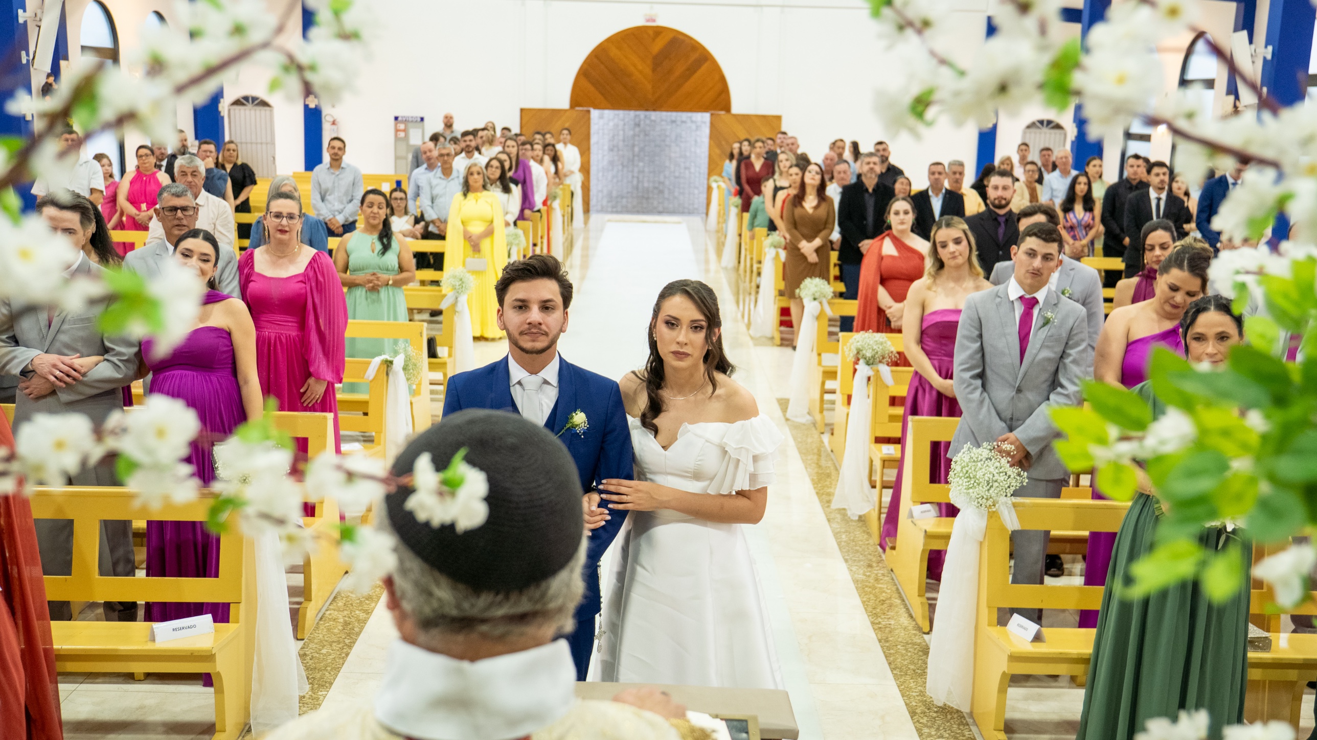 Noivos no altar, vistos do lugar do padre, com os convidados ao fundo