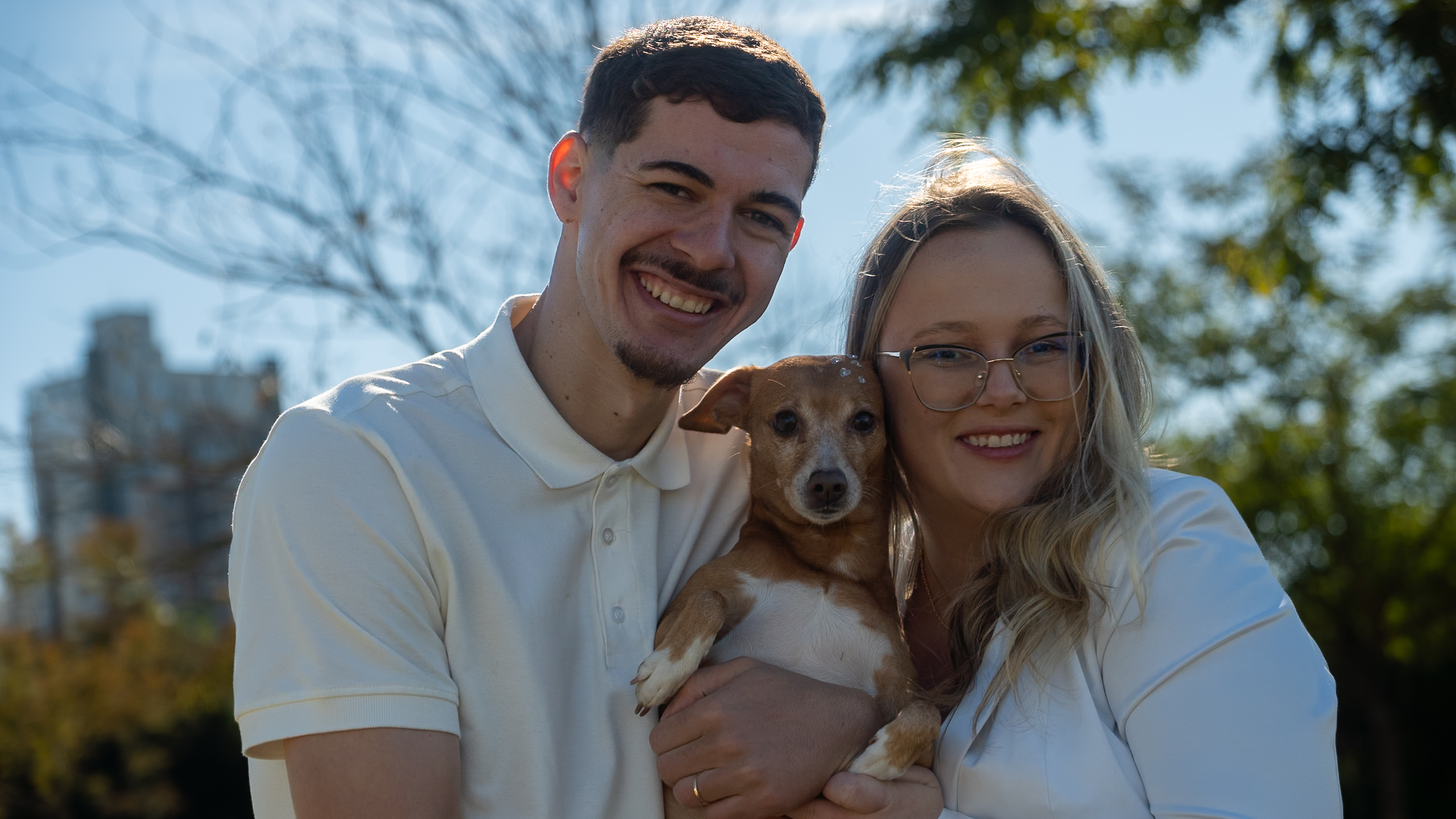 Casal sorrindo com o cachorro no colo