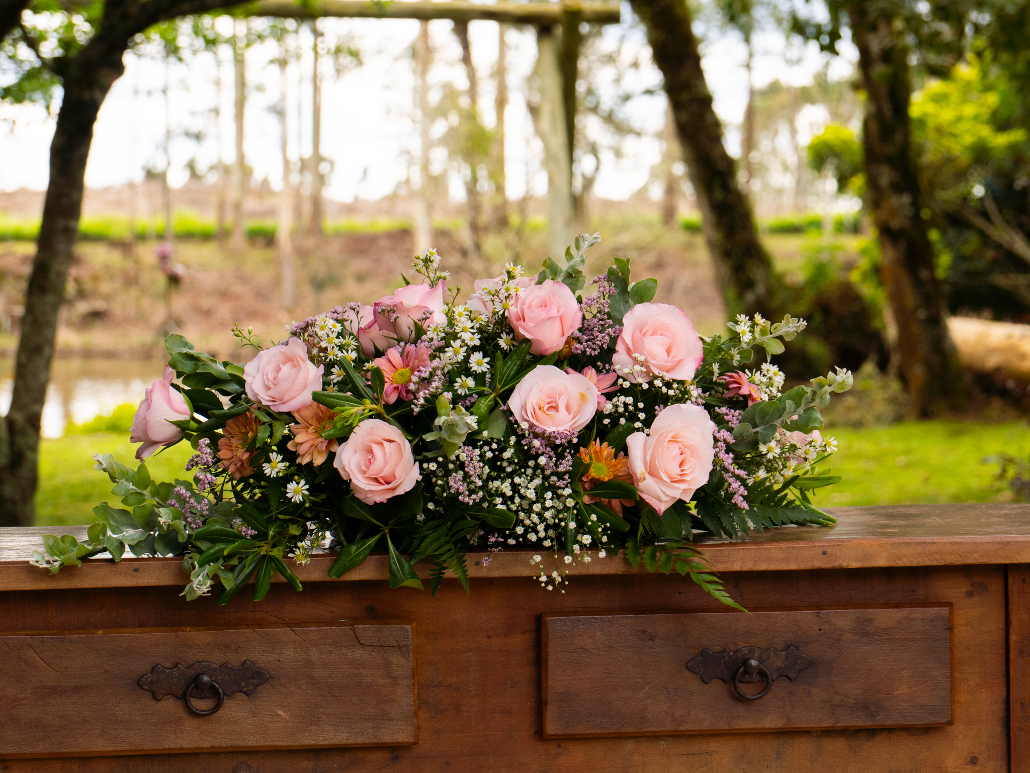 Arranjo de rosas sobre a mesa rústica do altar, com o jardim ao fundo