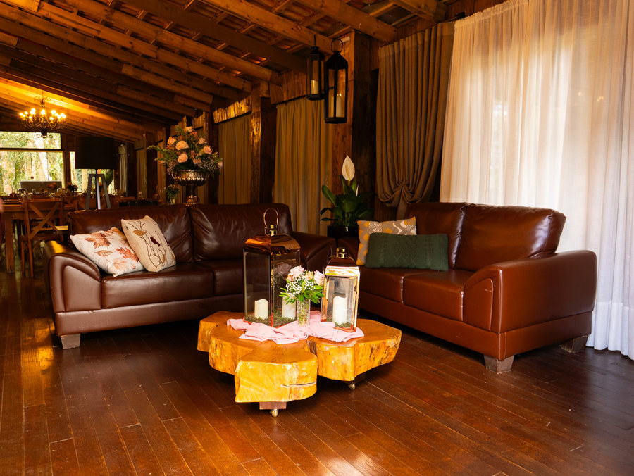 Lounge com sofás de couro, mesa de tronco e lanternas