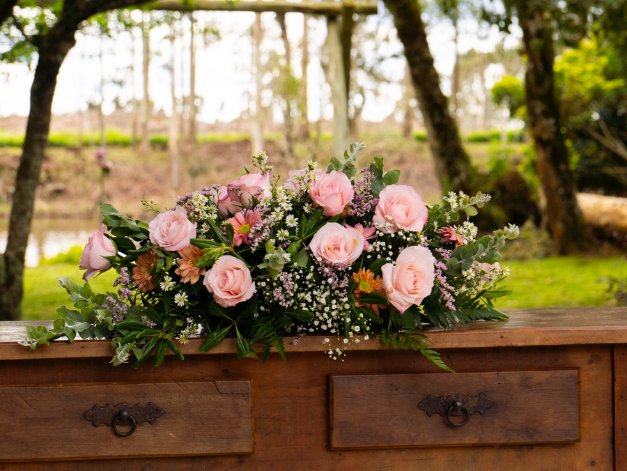 Arranjo de rosas sobre a mesa rústica do altar, com o jardim ao fundo