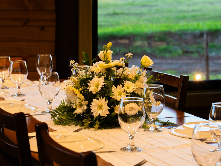 Arranjo de flores brancas sobre a mesa posta, com o gramado ao fundo