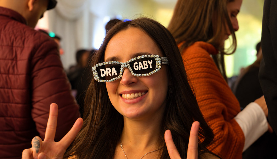 Formanda sorrindo com óculos de brilhantes escritos "Dra Gaby"