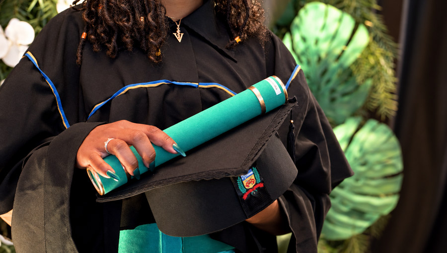 Formanda segurando o canudo do diploma sobre o capelo