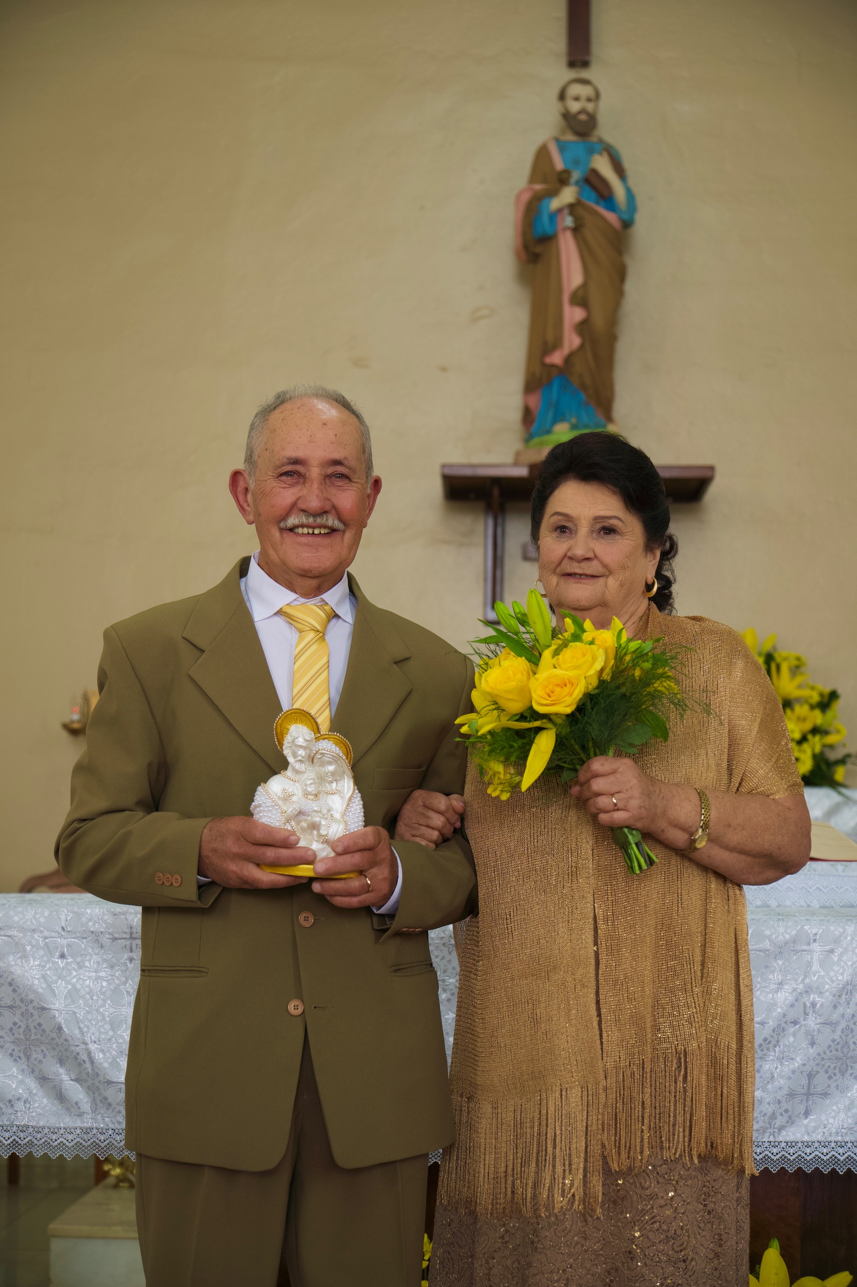 Casal no altar da igreja, ela com um buquê de rosas amarelas